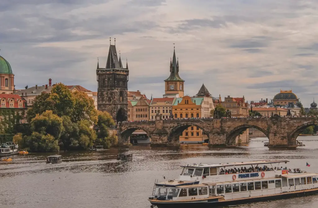 Charles Bridge Prague skyline with historic towers and a Prague Boats tour vessel on the Vltava River