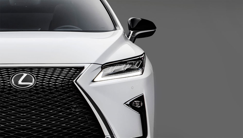Close-up of white Lexus front grille and LED headlight, luxury SUV front fascia on gray background