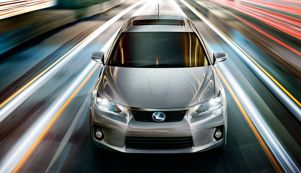 Silver Lexus sedan with headlights on speeding on illuminated urban road with dynamic light trails and motion blur