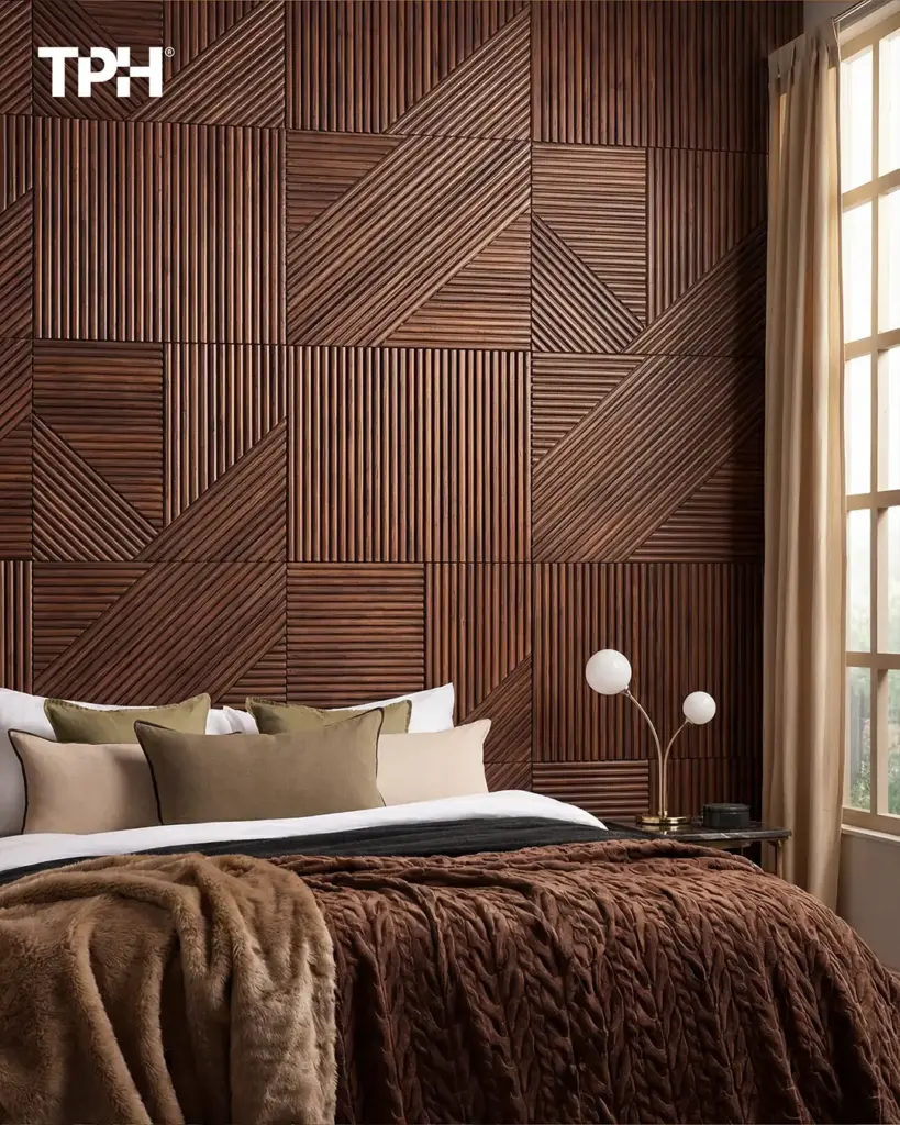 Modern bedroom with geometric textured wood accent wall, layered brown bedding, neutral pillows and brass bedside lamp.