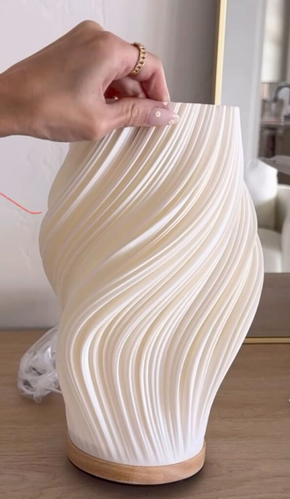 White sculptural wavy ribbed table lamp with wood base, hand adjusting top, modern bedside decor lamp.