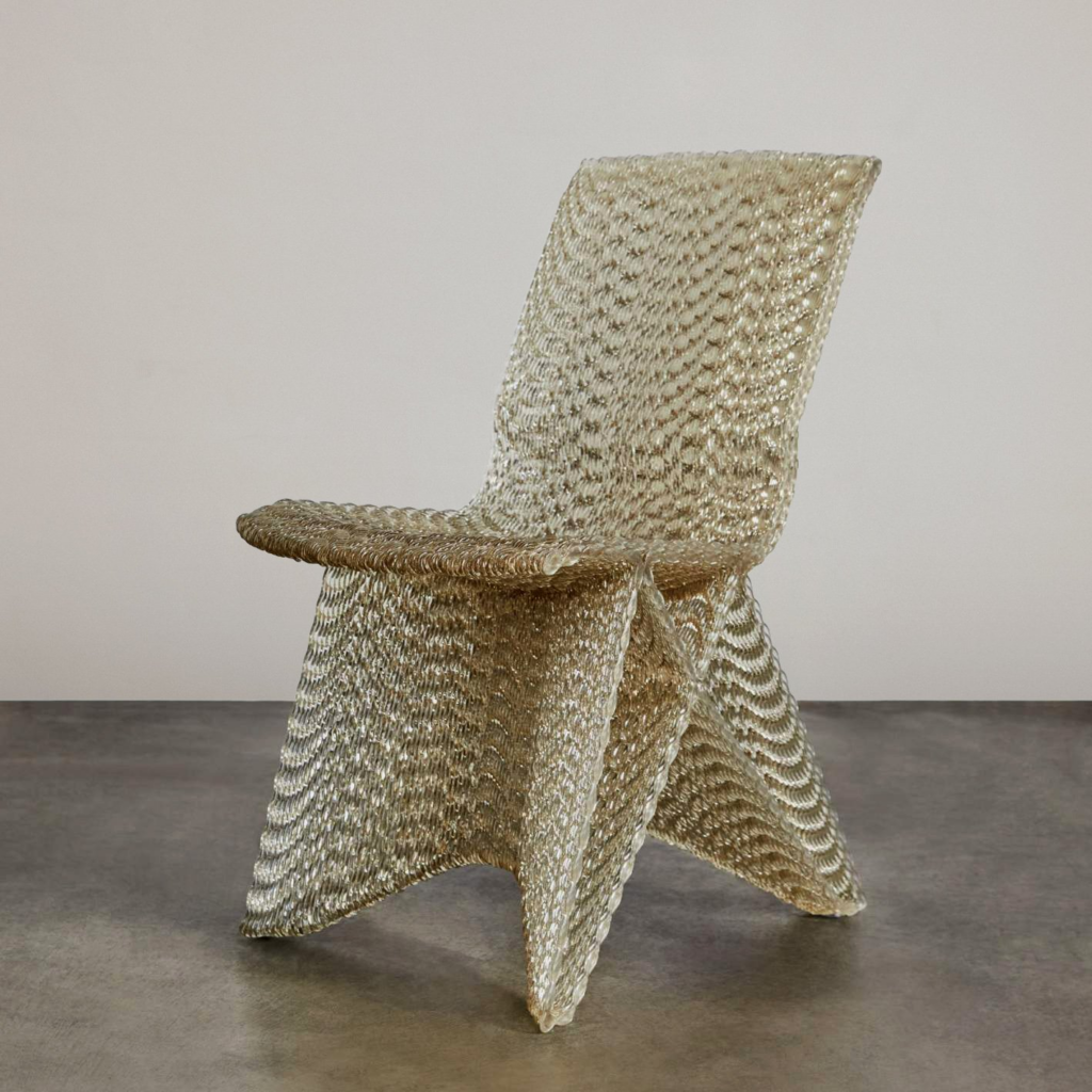 Woven metallic gold accent chair with braided texture, sculptural modern design on concrete floor