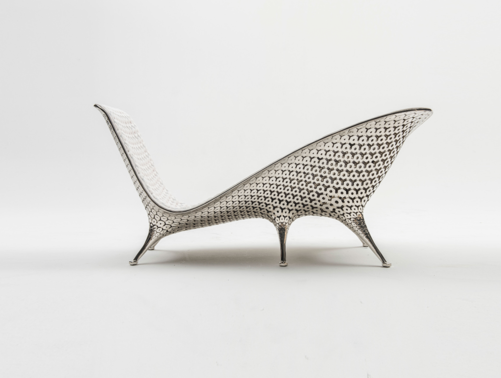 Modern designer metallic chaise lounge with honeycomb hexagonal pattern on white background