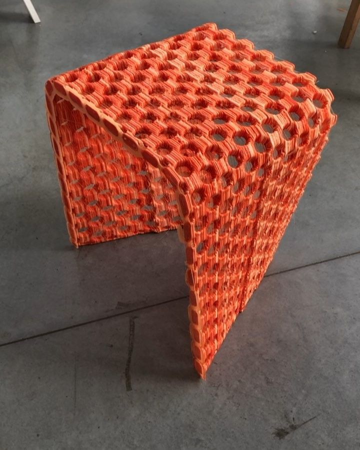 Orange honeycomb-pattern stool with hexagonal cutouts on concrete floor