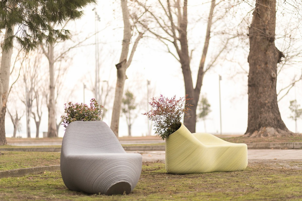 Contemporary outdoor bench-planters (gray and pale green) with shrubs in a tree-lined park