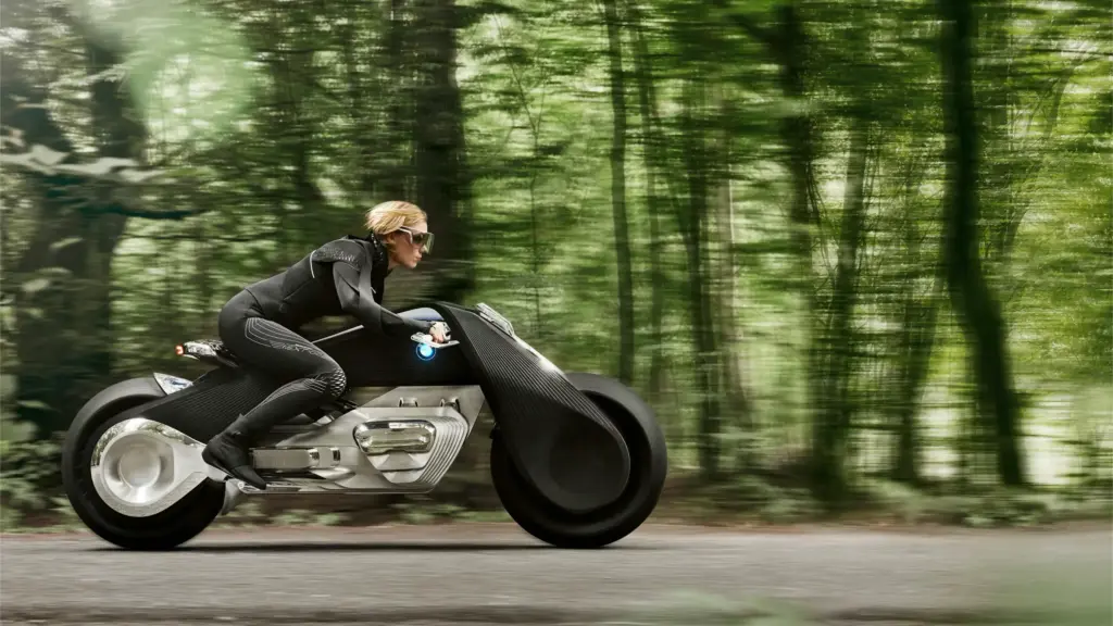 Female rider on futuristic electric concept motorcycle speeding along a tree-lined forest road, motion blur