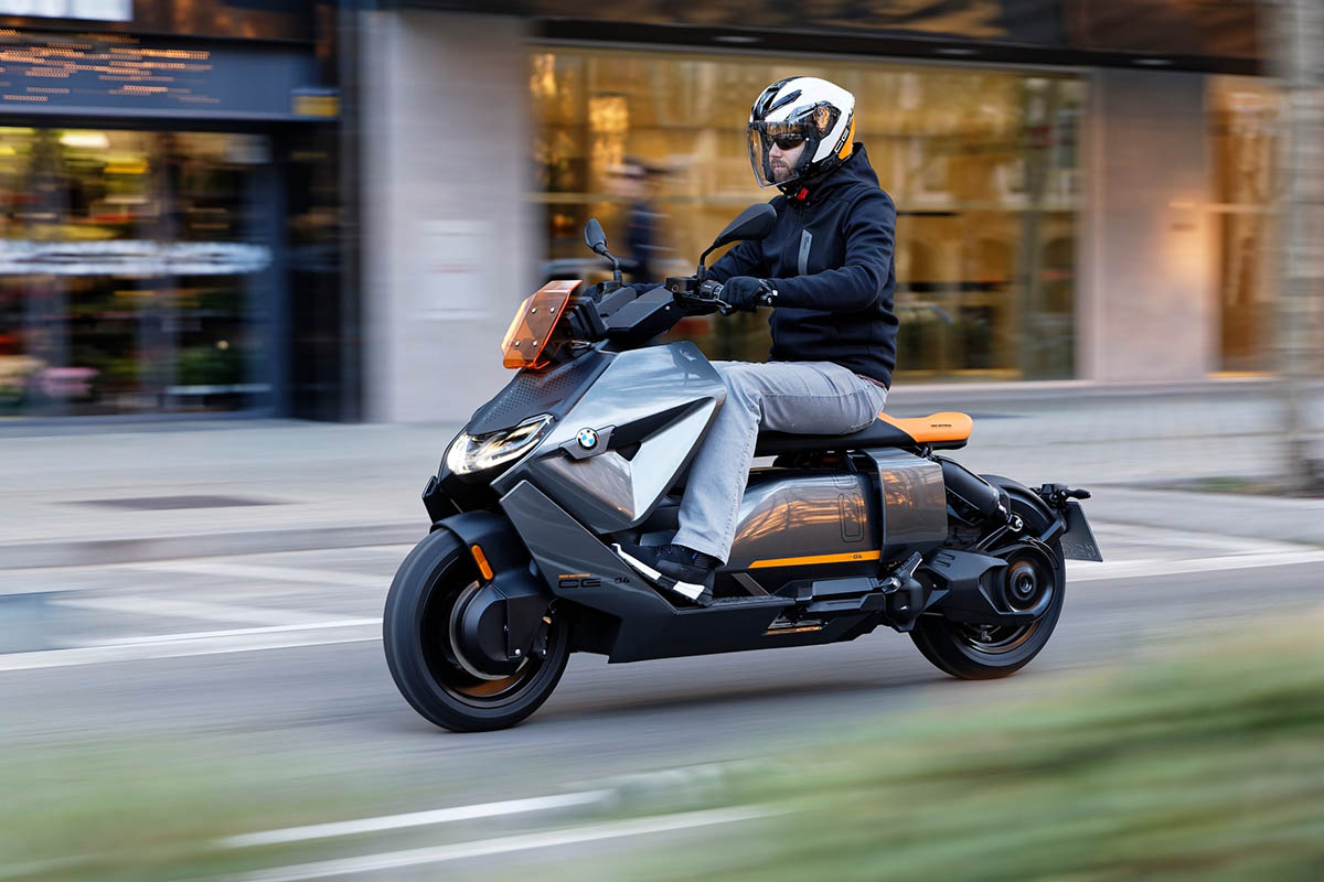 Man commuting on a BMW CE 04 electric scooter in city, modern gray-orange urban e-scooter