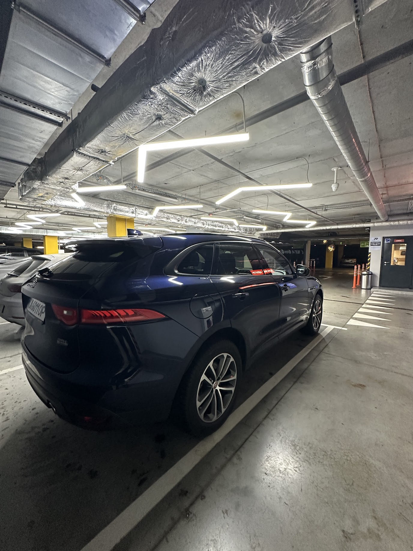 image Blue SUV parked in underground concrete parking garage under geometric LED ceiling lights | Sky Rye Design Blue SUV parked in underground concrete parking garage under geometric LED ceiling lights