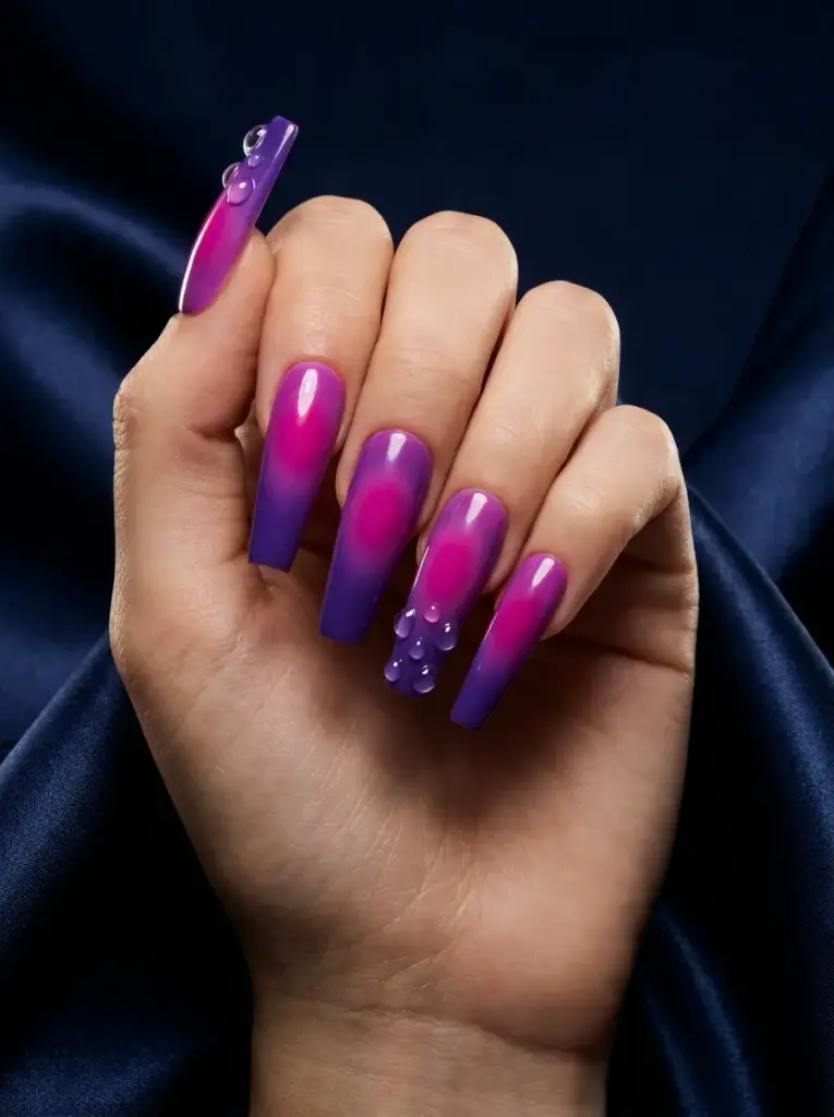 Hand with long coffin ombre nails pink-to-purple, glossy finish, 3D water-drop accents on ring and thumb.
