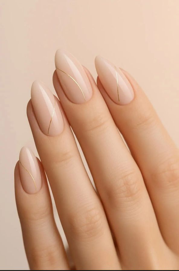 Nude almond nails with thin gold accent lines, glossy minimalist manicure close-up