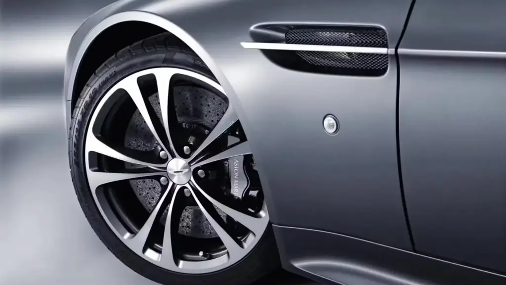 Close-up of Aston Martin alloy wheel and brake caliper on metallic gray luxury sports car