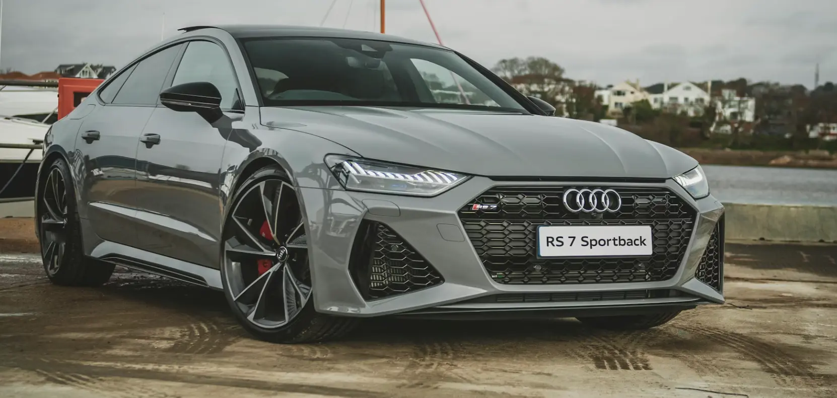 Front-side view of gray Audi RS 7 Sportback with LED headlights and black alloy wheels by waterfront