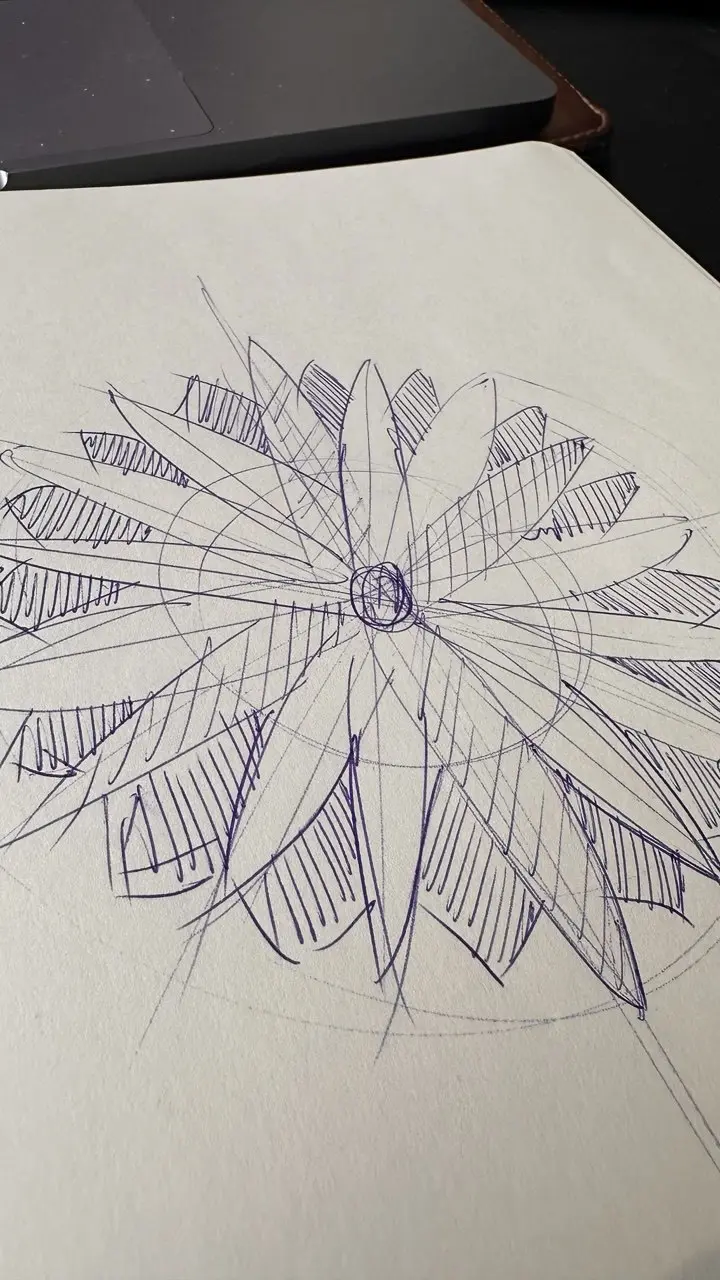 photo_2026-05-18_11-50-21 Blue-ink hand-drawn floral/mandala sketch on notebook page beside laptop, radial petals with hatched shading. | Sky Rye Design Blue-ink hand-drawn floral/mandala sketch on notebook page beside laptop, radial petals with hatched shading.