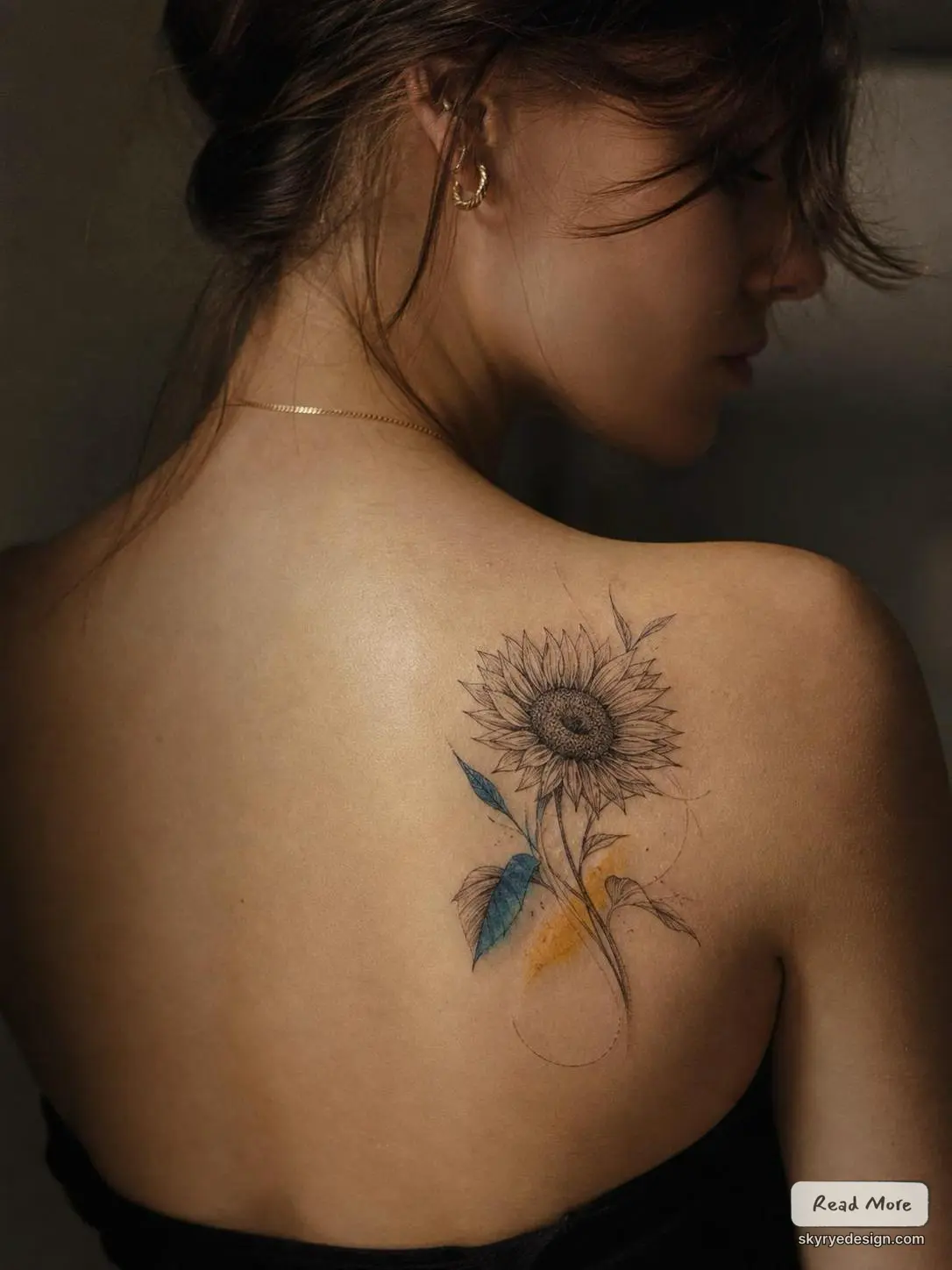 Sunflower tattoo on shoulder blade: delicate fine-line sketch with blue watercolor leaves on a woman's upper back