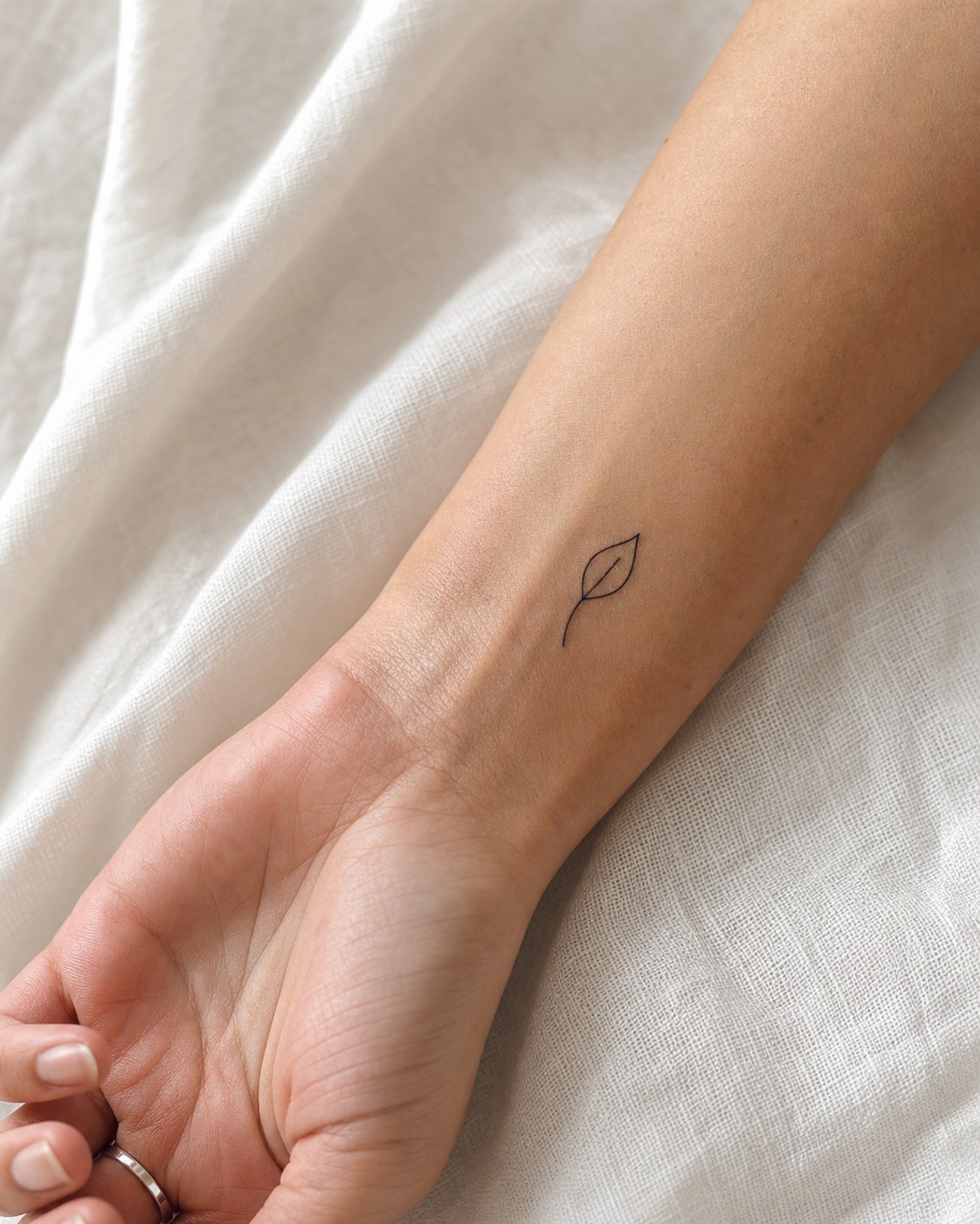 Delicate single-line leaf tattoo Delicate single-line leaf tattoo on the forearm with fine black ink and soft natural light. | Sky Rye Design Delicate single-line leaf tattoo on the forearm with fine black ink and soft natural light.