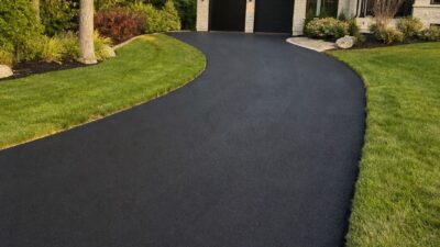 Fresh asphalt driveway curving toward a contemporary home garage.