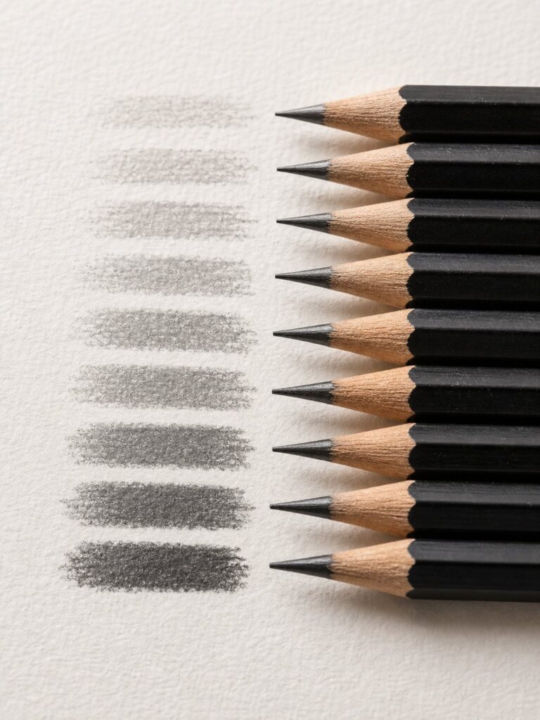 graphite-pencil-grades-value-range Sharpened black graphite pencils lined right with graduated gray shading swatches on textured drawing paper | Sky Rye Design Sharpened black graphite pencils lined right with graduated gray shading swatches on textured drawing paper
