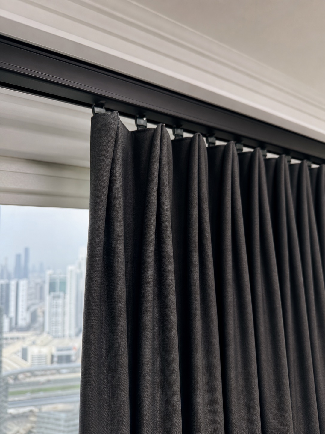 Matte black ceiling-mounted curtain track with neatly hung charcoal blackout curtains.