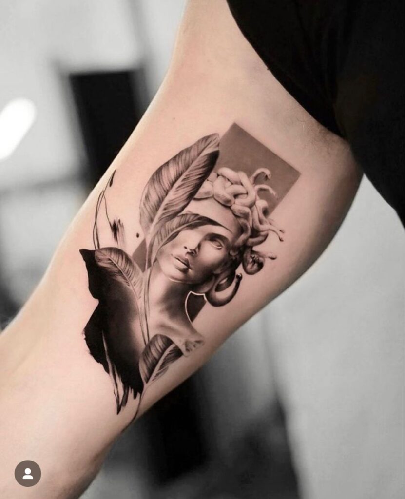 Black-and-gray realistic Medusa tattoo design with snakes, feathers and abstract brush strokes on inner bicep