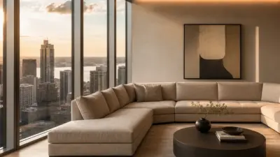 Luxury high-rise living room with beige sectional and floor-to-ceiling windows overlooking city skyline at sunset