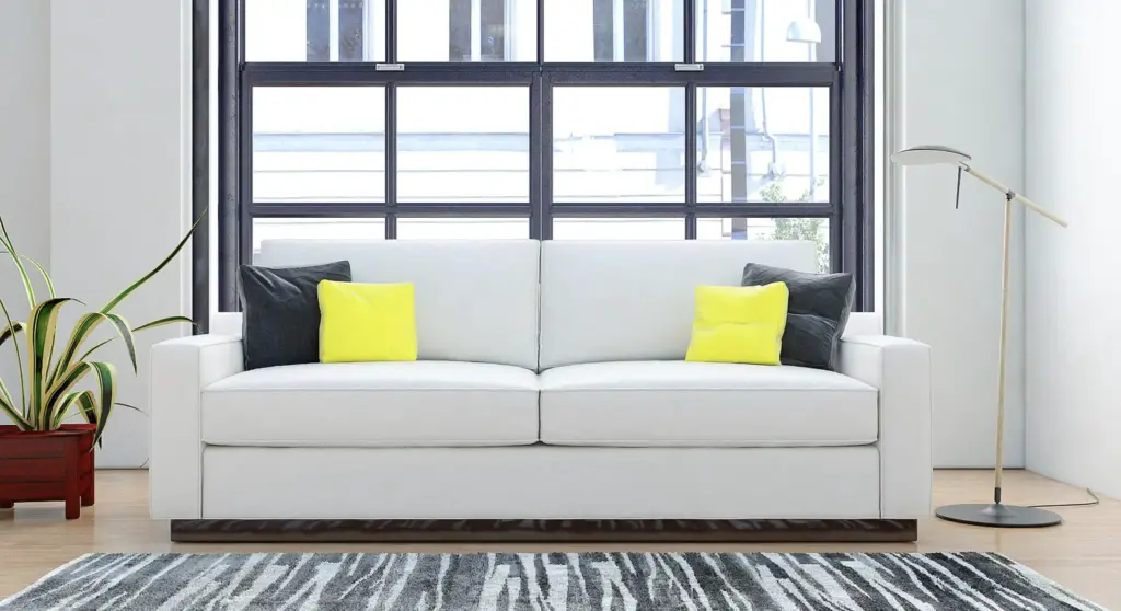 Modern living room with white sofa, yellow accent pillows, dark cushions, industrial grid window, floor lamp, potted plant