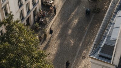 A walkable European residential street with trees, cyclists, pedestrians, and cafe terraces.
