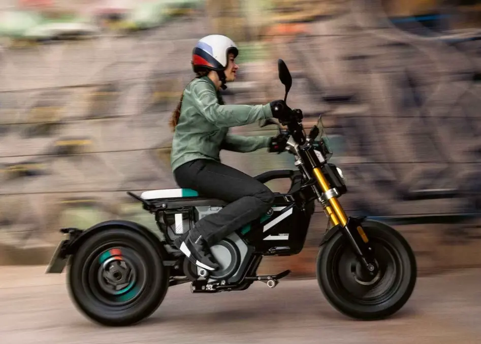 Electric motorcycle urban commuter: woman in helmet riding a modern electric bike through blurred city street