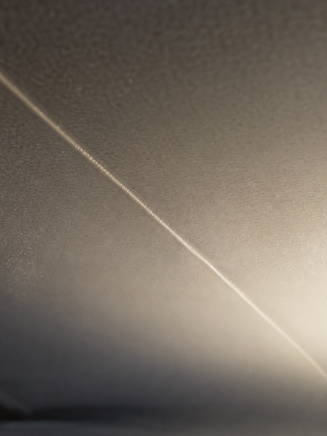 Close-up inspection of a welded PVC stretch ceiling seam under raking light.