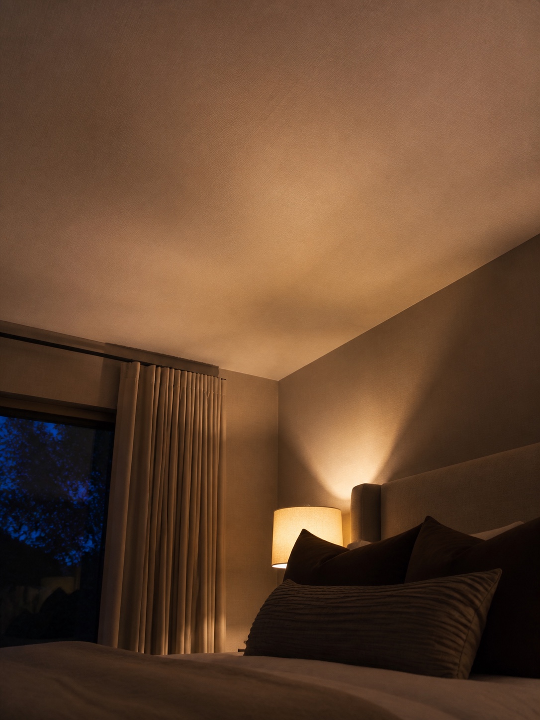 Seamless matte fabric stretch ceiling in a quiet bedroom at dusk.