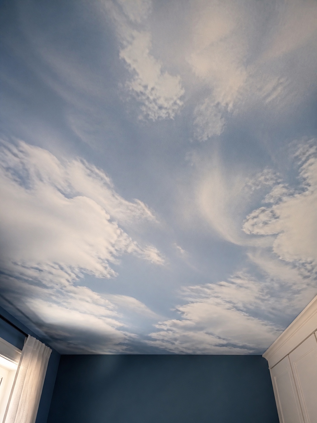 Printed sky scene stretch ceiling viewed from below in a bedroom.