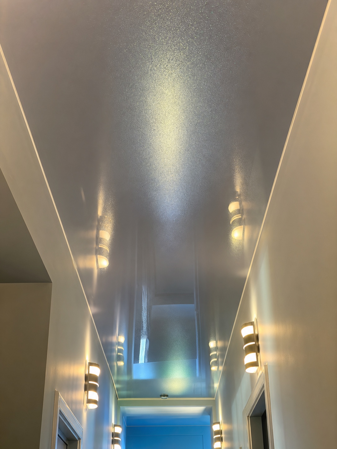 Metallic pearlescent stretch ceiling running through a narrow hallway.