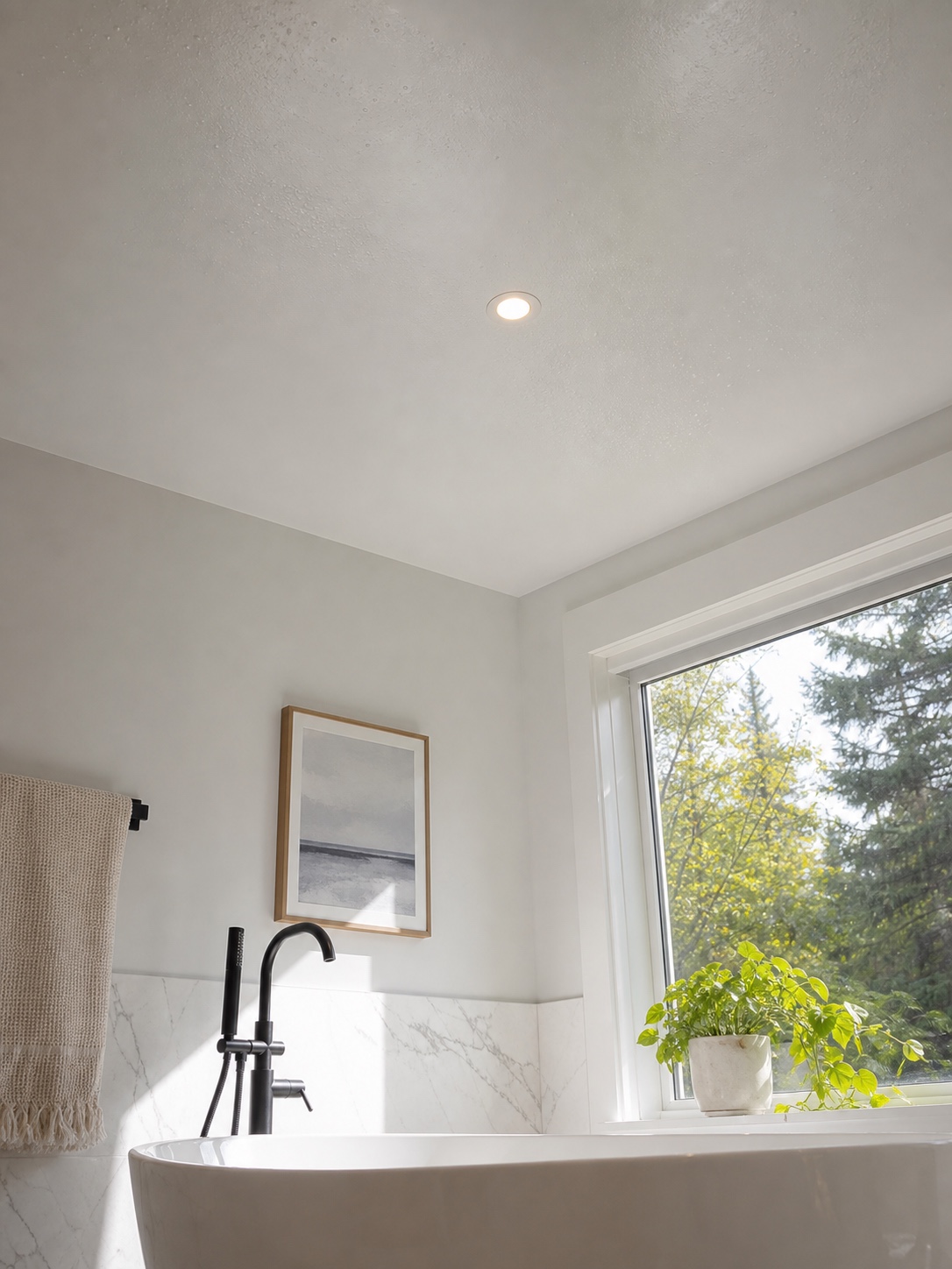 Waterproof satin PVC stretch ceiling above a bright bathroom tub.