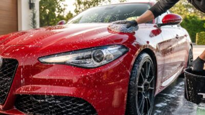 Red Alfa Romeo-inspired sports coupe being hand washed with a microfiber mitt during careful detailing.