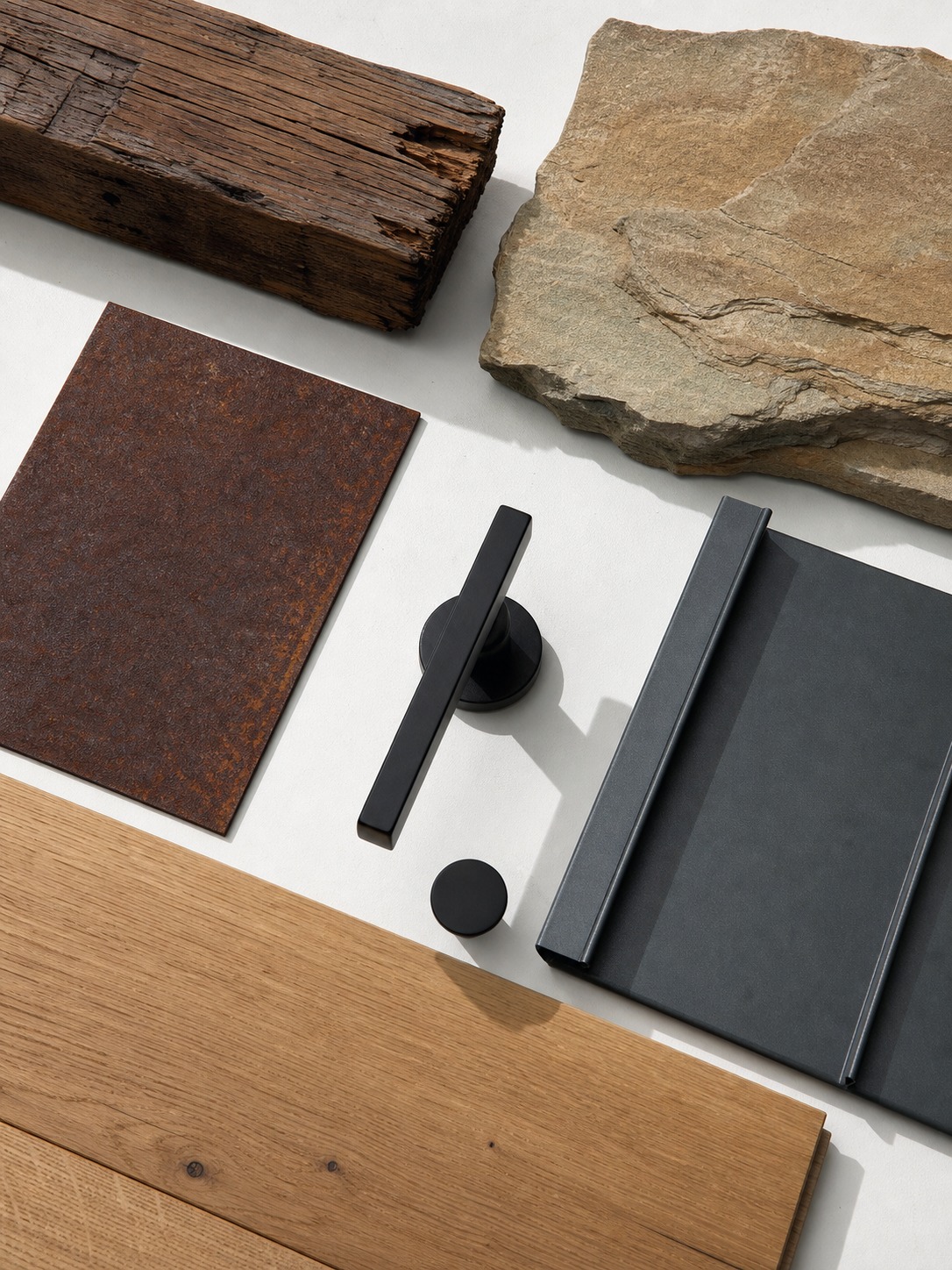 Flat lay of reclaimed timber, sandstone, corten steel, oak flooring, black hardware, and standing seam metal samples
