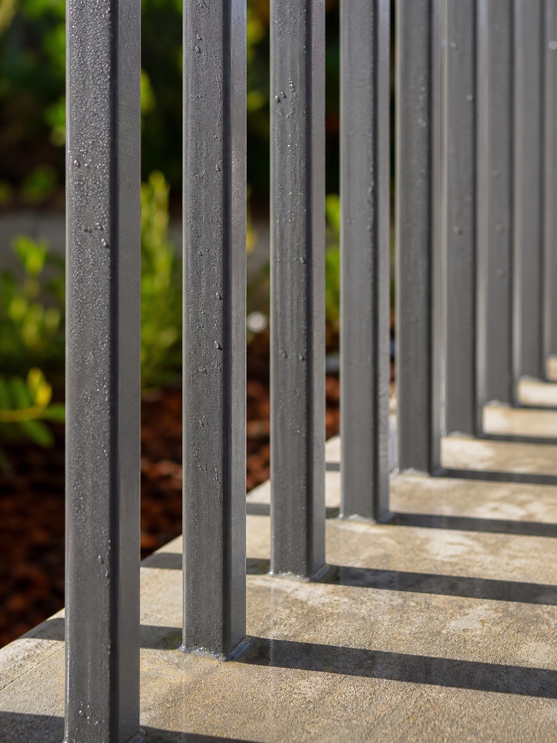 Close-up of aluminum fence pickets with standard spacing and light passing through
