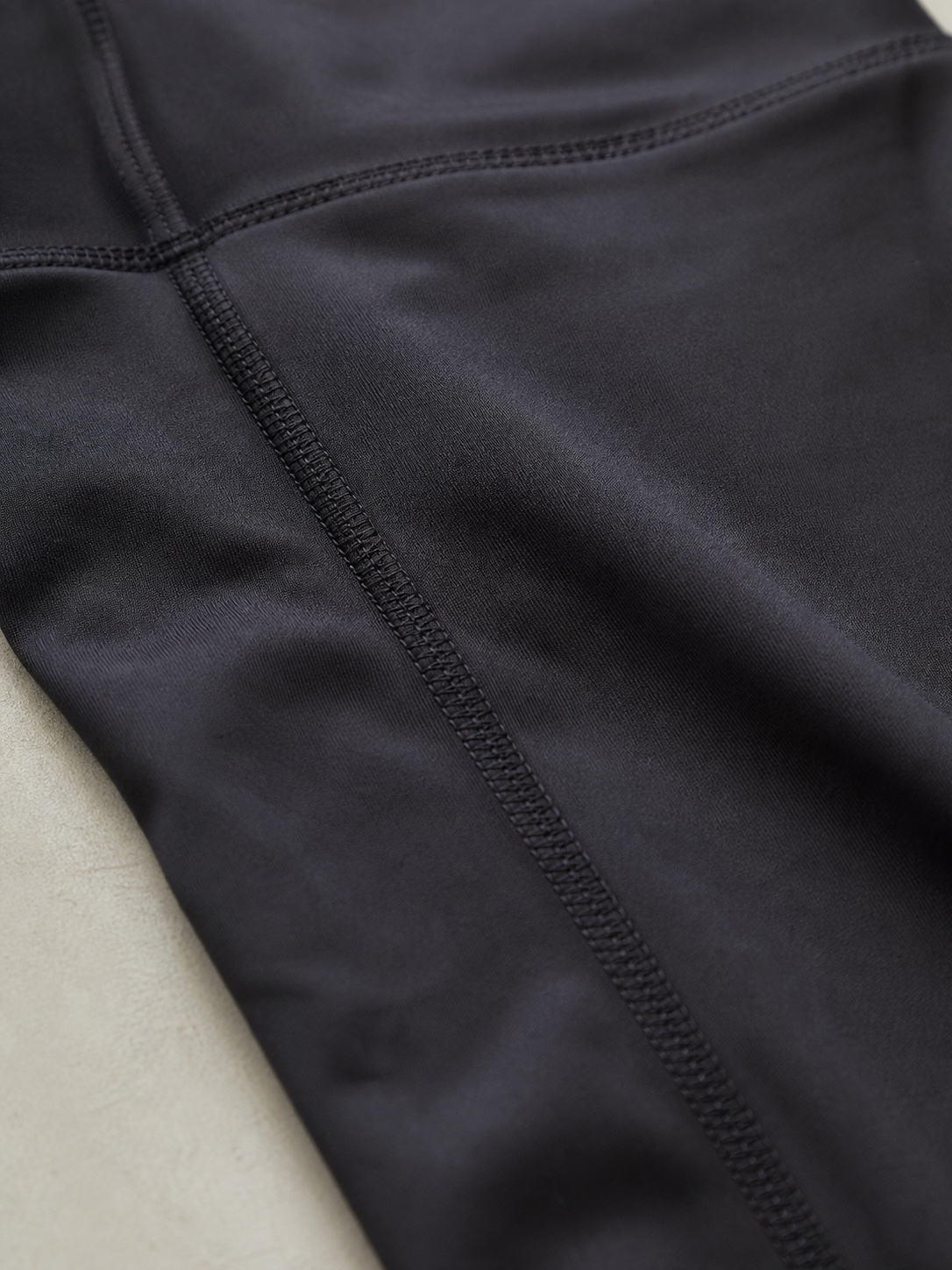 Interior of black activewear leggings showing a flatlock overlock seam on stretch fabric.