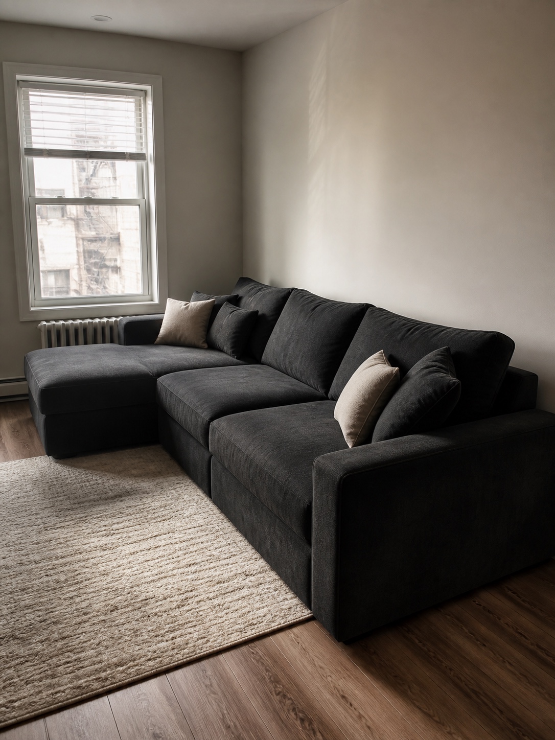 Dark sofa same small room contrast comparison Deep charcoal sofa appearing visually heavier in a small light-walled room. | Sky Rye Design Deep charcoal sofa appearing visually heavier in a small light-walled room.