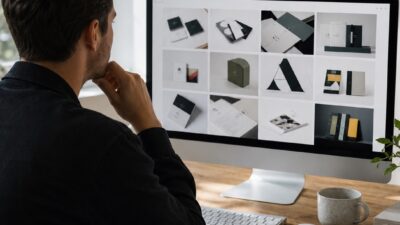 Designer reviewing a graphic design portfolio website on a large monitor in a clean studio.