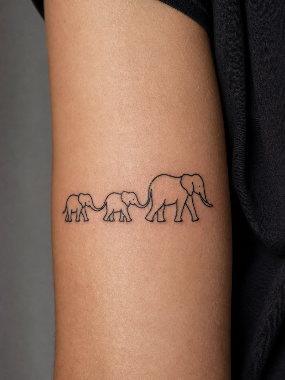 Minimal black ink elephant family tattoo with a mother and two calves walking in line.