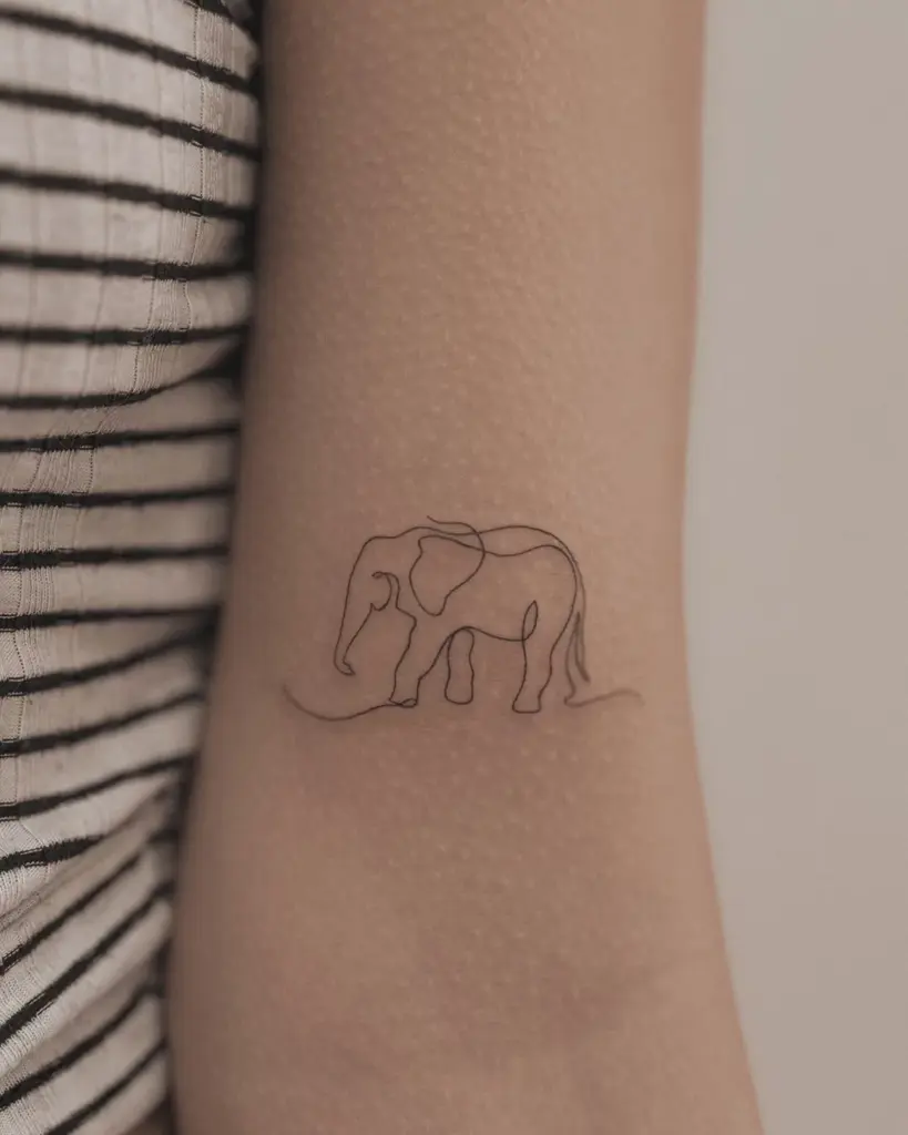 Minimalist single-line elephant tattoo on inner forearm, close-up of thin black outline next to striped shirt