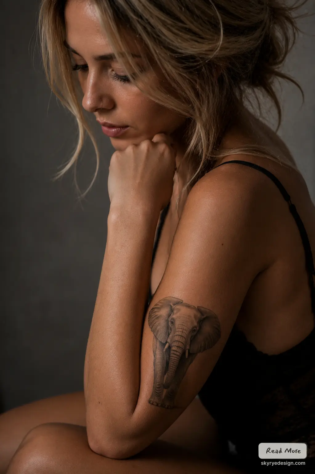 Close-up portrait of woman with realistic elephant tattoo on upper arm, pensive pose, soft light, neutral background