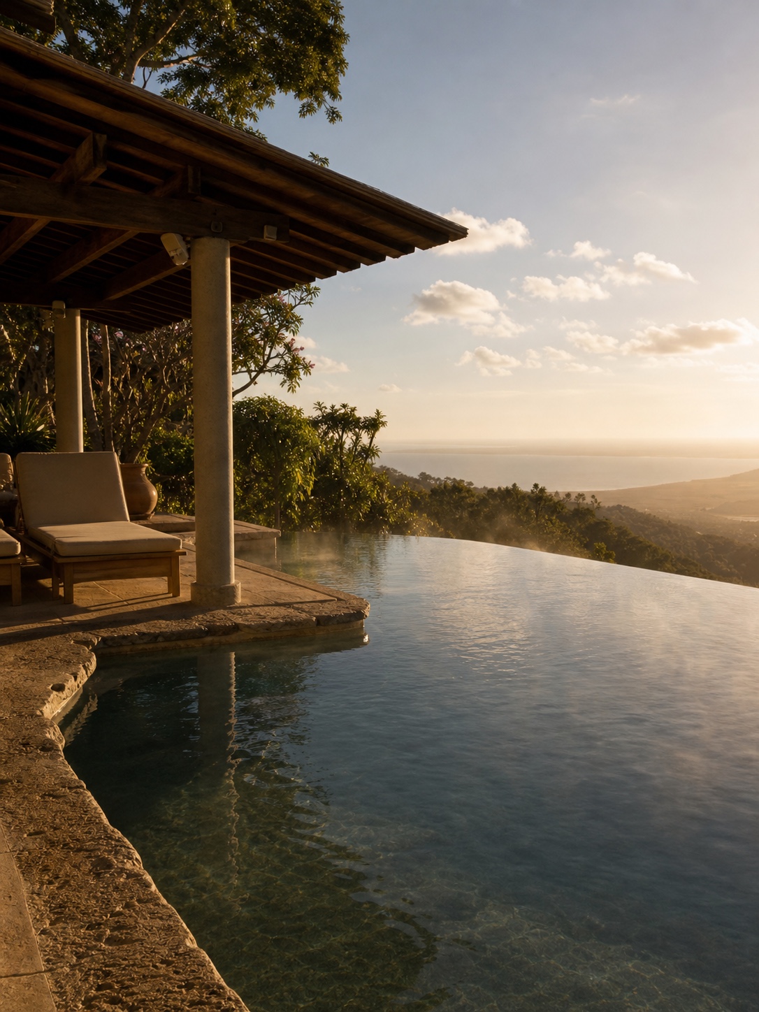 An infinity-edge pool beside a shaded terrace with warm light reflecting from the water.