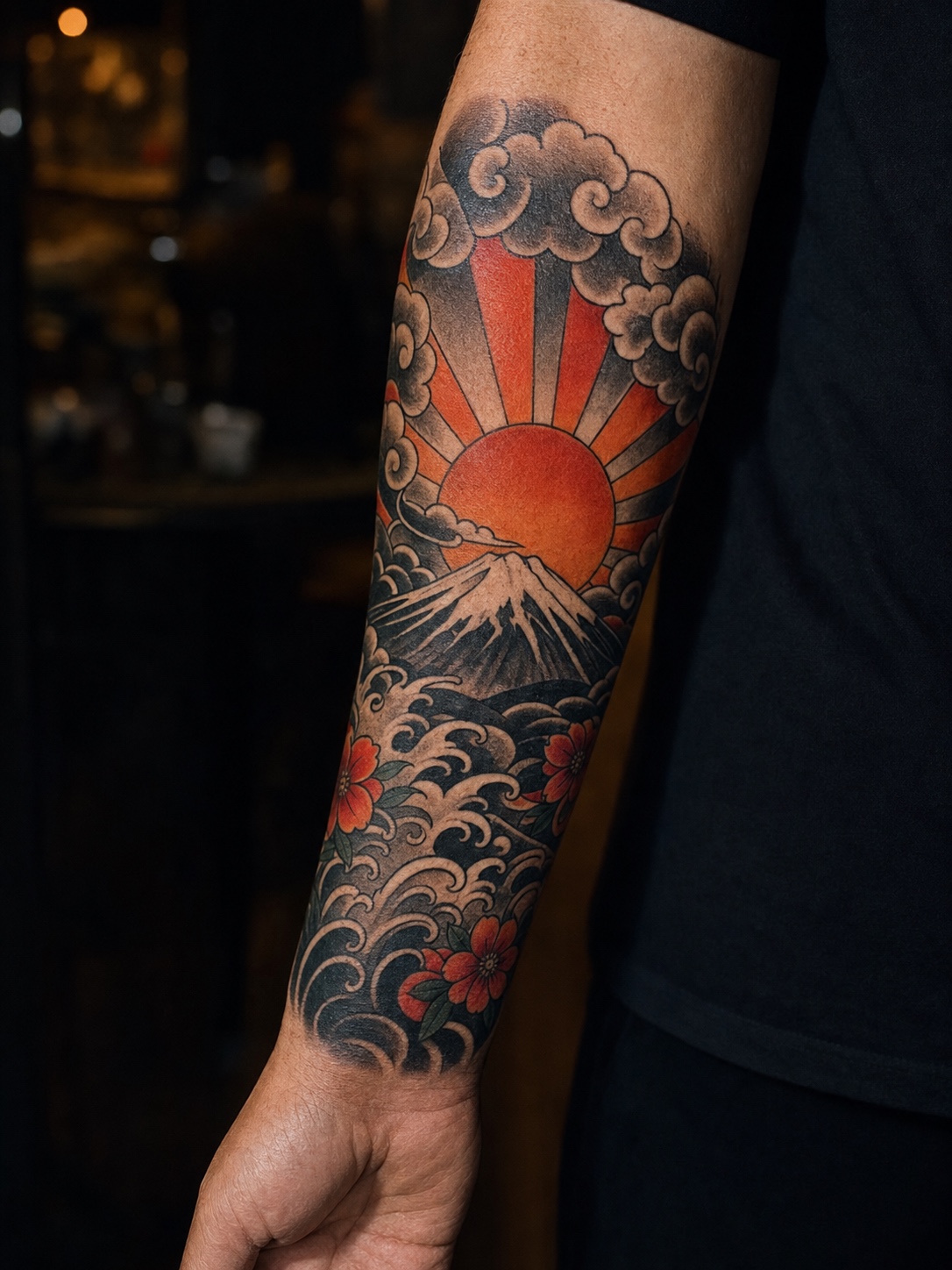Japanese traditional sunrise forearm tattoo with bold clouds and red-orange rays.