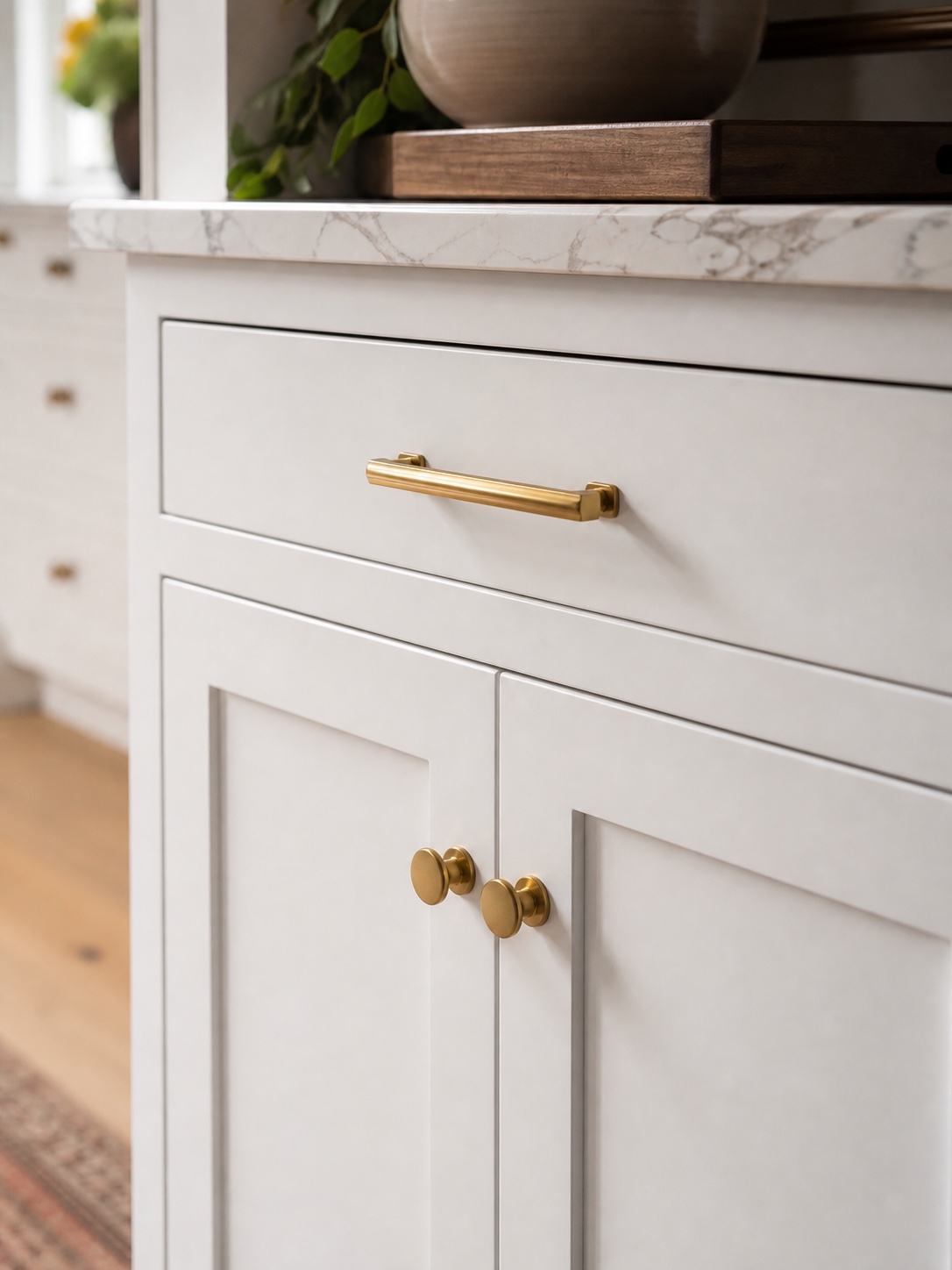 Fresh white Shaker kitchen cabinets with brushed brass hardware and a marble-look countertop edge.