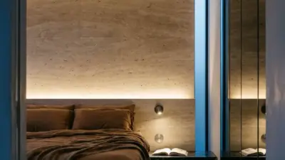 Luxury modern minimalist bedroom with brown bedding, stone accent wall, warm LED strip lighting and mirrored wardrobe.