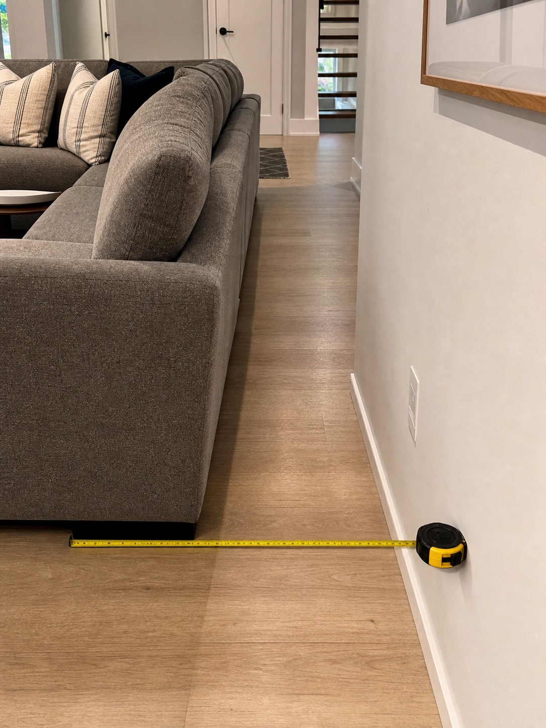 Corner sectional sofa with a tape measure showing walkway clearance between the sofa and wall.