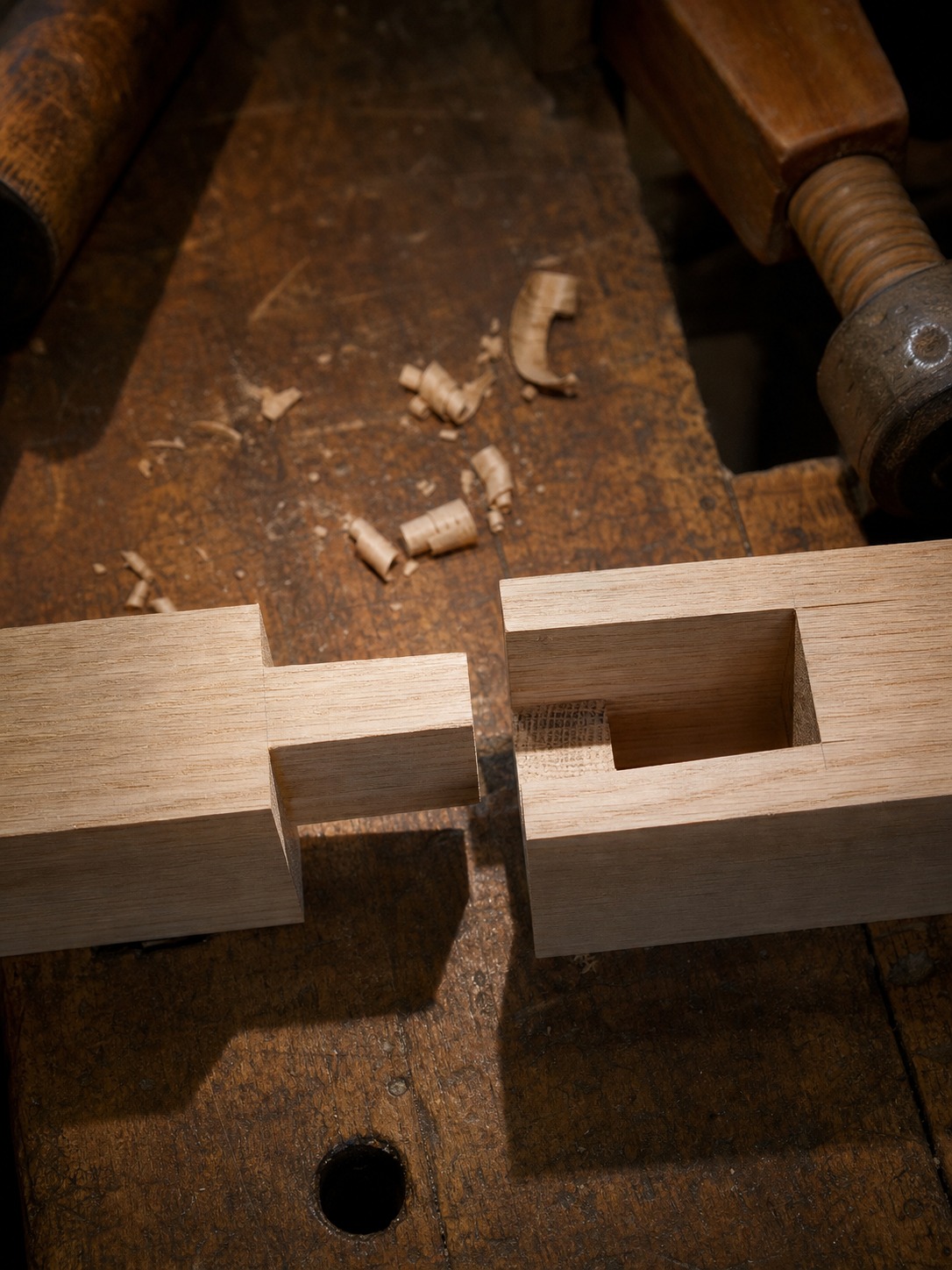 Fresh mortise-and-tenon joint being dry-fitted in solid white oak on a workshop bench.