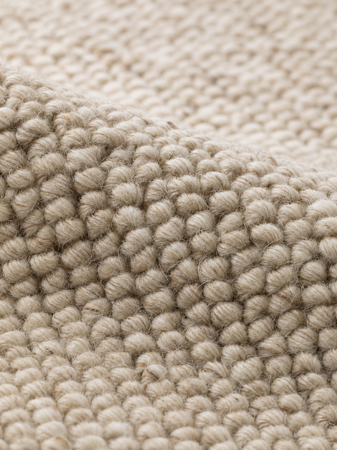 Macro view of oatmeal berber loop-pile carpet with individual loops in sharp detail.