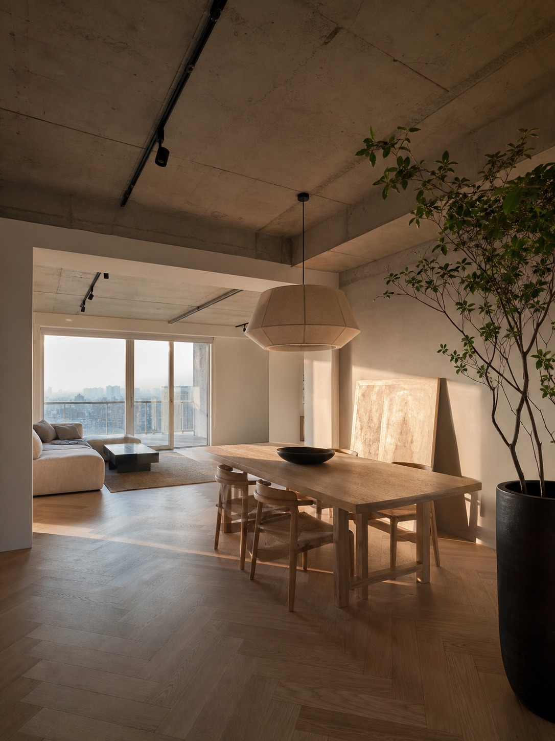Open-plan apartment render with raw concrete ceiling, pale oak floor, ash dining table, artwork, and warm light.