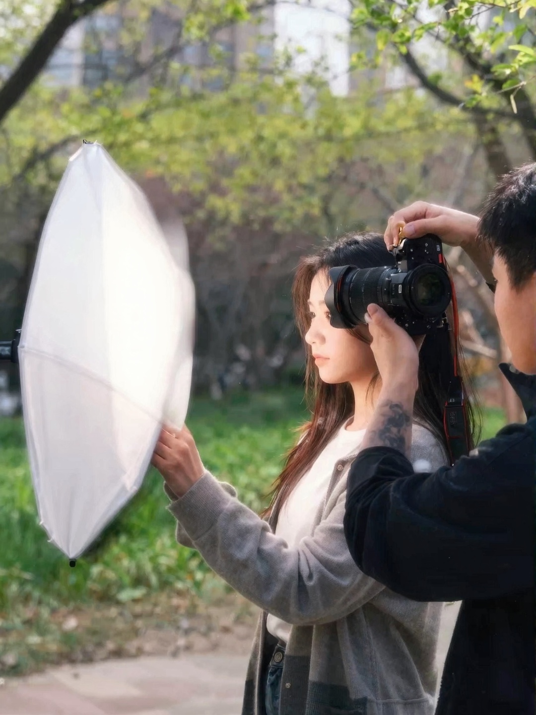 Park Reflector Portrait Session Photographer taking a park portrait of a woman while a white reflector bounces natural sunlight | Sky Rye Design Photographer taking a park portrait of a woman while a white reflector bounces natural sunlight